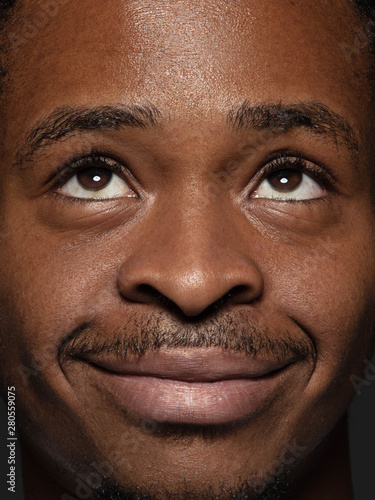 Close up portrait of young and emotional african-american man. Highly detail photoshot of male model with well-kept skin and bright facial expression. Concept of human emotions. Looking up and smile.