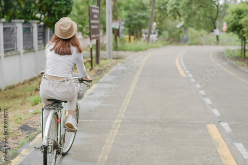 Wallpaper Mural Pretty girl with straw hat is happy riding with bike down wide beautiful park alley with trees around on sunny summer day. Torontodigital.ca