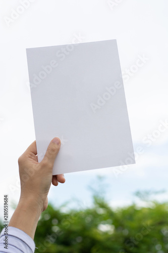 Woman holding paper blank of drawing paper paper with natural background.