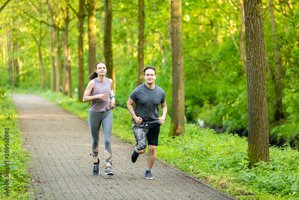 young woman and man running in a forest and making fitness young woman and man running in a forest and making fitness