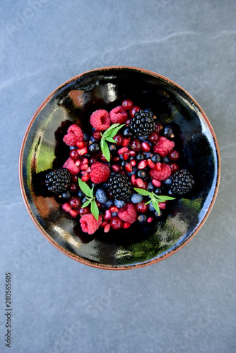 breakfast bowl with fresh berries, blackberries, raspberries, blueberries, raisins, pomegranate, mint and linseed