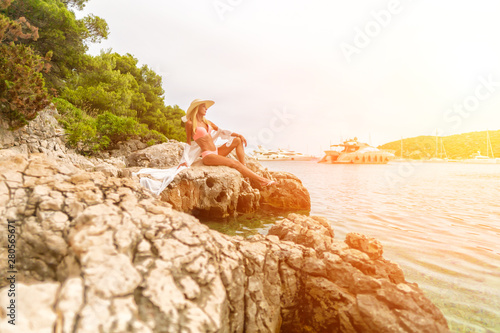 Young Girl Sitting on the rocks Alone and looking at the sea photo