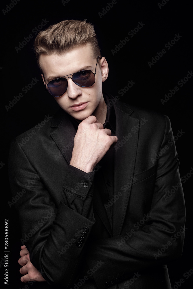 Obraz premium young man with black glasses in black jacket on black background