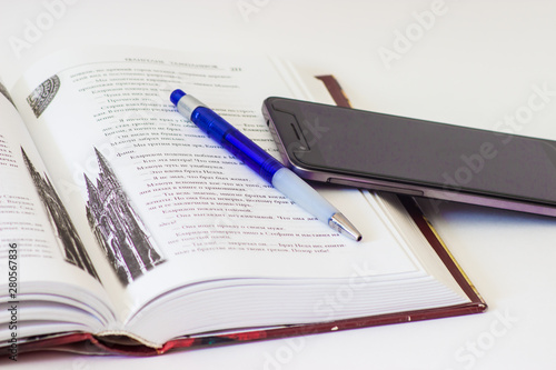 book, pen and phone on a white background