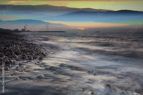 Rocks on stone beach at sunset. Beautiful beach sunset sky. Twilight sea and sky