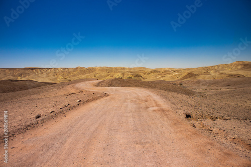 desert nature scenery landscape with lonely trail in sand dunes wilderness environment and horizon mountains background 