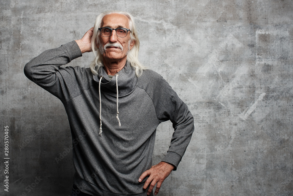 Handsome gray haired grandfather with mustache and glasses poses holding head in studio