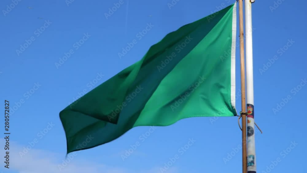 Green flag on the beach informing about safety. The rescuer is present on the beach. You can swim safely. Green flag on the beach informing about safety. The rescuer is present on the beach. You can swim safely.