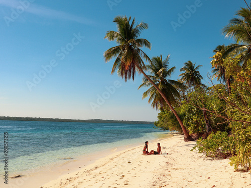 Fototapeta Naklejka Na Ścianę i Meble -  Lovely couple walking at the white sandy beach with palm trees in Onok Island in Balabac Philippines
