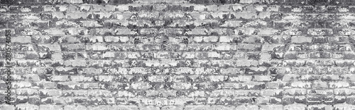 Wide light gray shabby brick wall texture. Old masonry with peeling white paint. Weathered brickwork panoramic vintage background