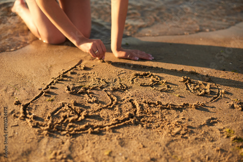 girl in love draws a heart on the sand by the sea