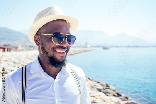 handsome african american person casual fashion look outfit in straw hat,white shirt walking by Tyrkey coast