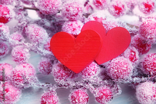 Two bright red hearts on branches with frosted berries