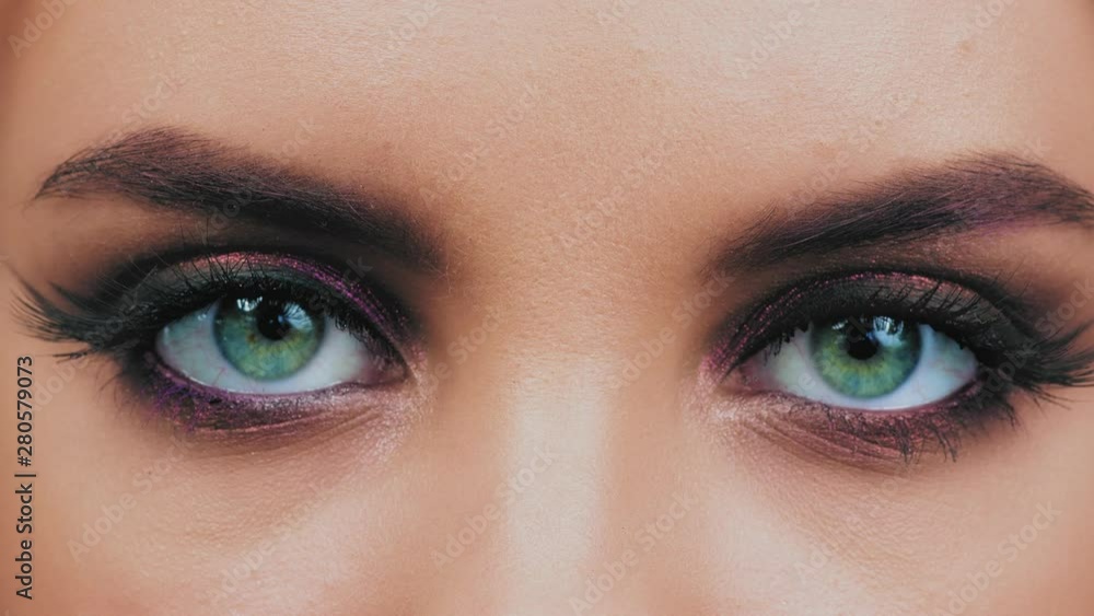 Amazing glance of eyes. Eyes of caucasian woman close up in glowing eye shadows and arrows looking at camera Amazing glance of eyes. Eyes of caucasian woman close up in glowing eye shadows and arrows looking at camera
