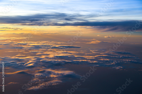 A Beautiful sunset sky above clouds with dramatic light. Cabin view from View from passenger's seat in airplane flying.