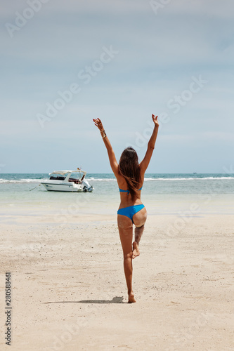 pretty woman posing in the sea, blue sky, hair wild, victory hand up!, outdoor portrait hipster, fashion model