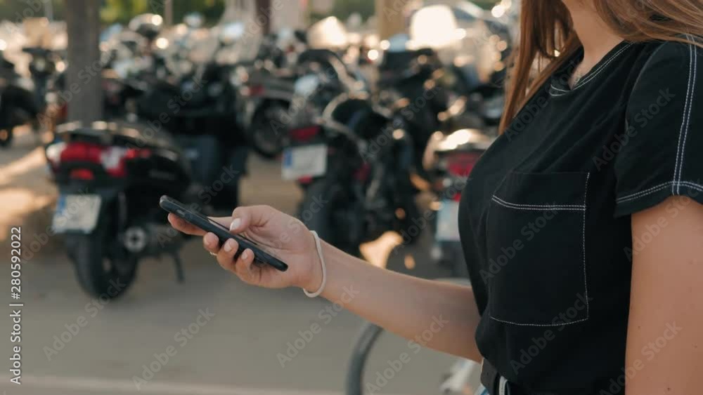 Woman checking smart phone showing screen on scooter parking. Motorbiker on her motorbike checking smart phone information Woman checking smart phone showing screen on scooter parking. Motorbiker on her motorbike checking smart phone information