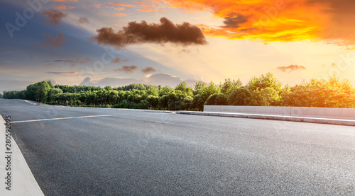 Asphalt highway and green forest with beautiful cloud landscape at sunset