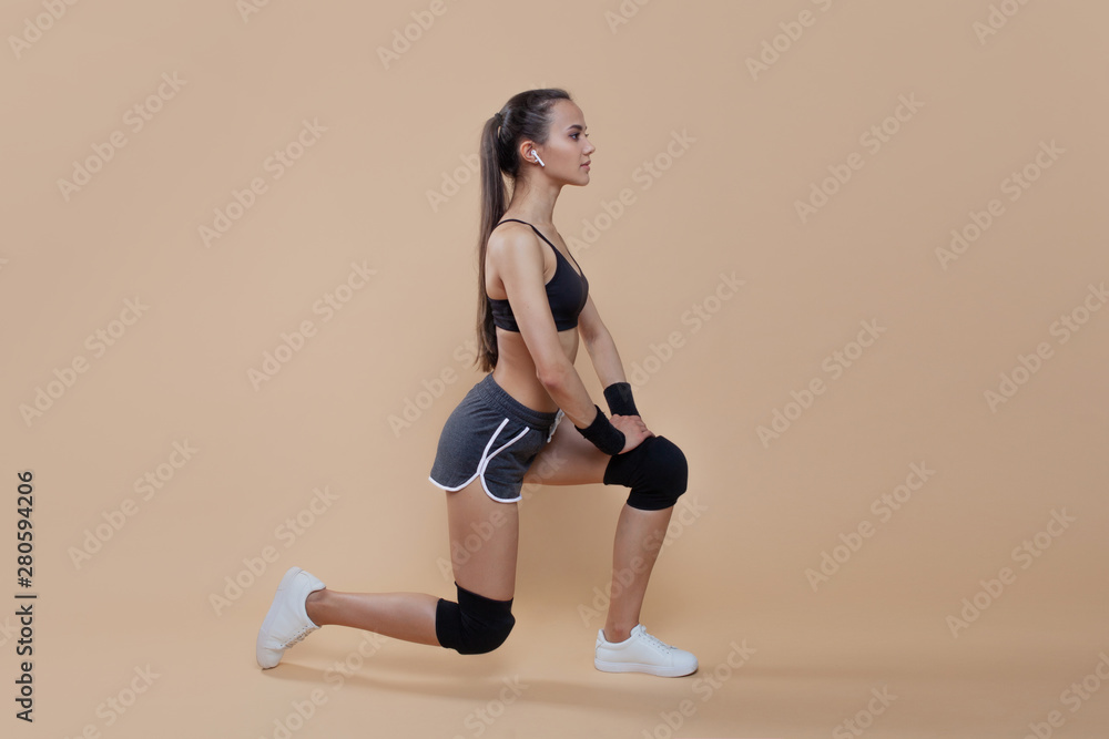 A young brunette girl standing on one knee. Knees protected by knee pads, on hands bandages. She prepared for training.