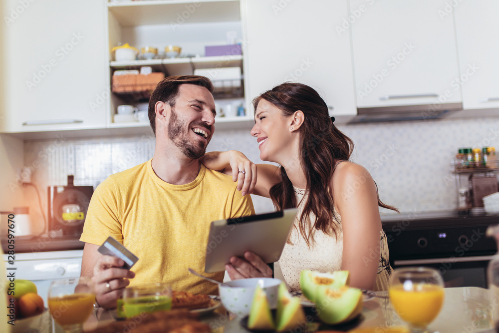 Smiling couple using digital tablet and credit card at home Smiling couple using digital tablet and credit card at home