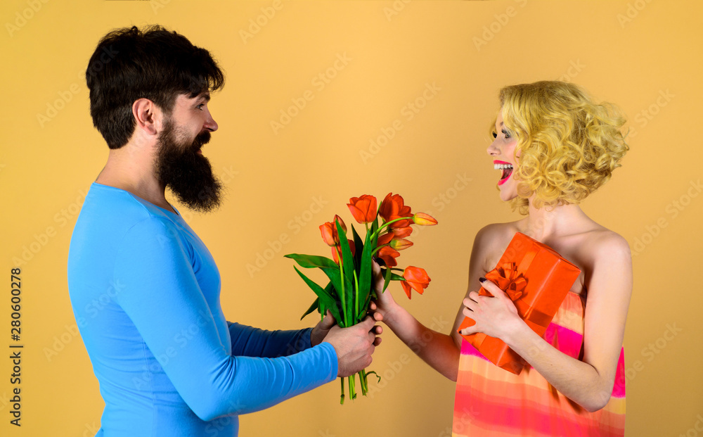 Man offering gift and bouquet for girlfriend in Valentines day. Stylish man giving his girlfriend present. Happy woman receiving gift and flowers from boyfriend. Holidays, love, relationship, dating. Man offering gift and bouquet for girlfriend in Valentines day. Stylish man giving his girlfriend present. Happy woman receiving gift and flowers from boyfriend. Holidays, love, relationship, dating.