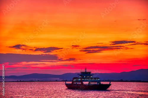 Ferry boat to the sea at sunset in the background of mountains and sun beams, run from Keramoti city to Thassos island in Greece © ververidis