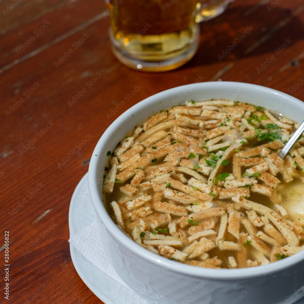 Bavarian pancake soup and a glass of beer, top view, cropped, on wooden table, bar setting Bavarian pancake soup and a glass of beer, top view, cropped, on wooden table, bar setting