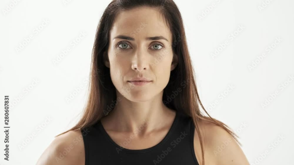 Close up view of serious beautiful sporty brunette woman in black sportswear looking at the camera over white background isolated Close up view of serious beautiful sporty brunette woman in black sportswear looking at the camera over white background isolated
