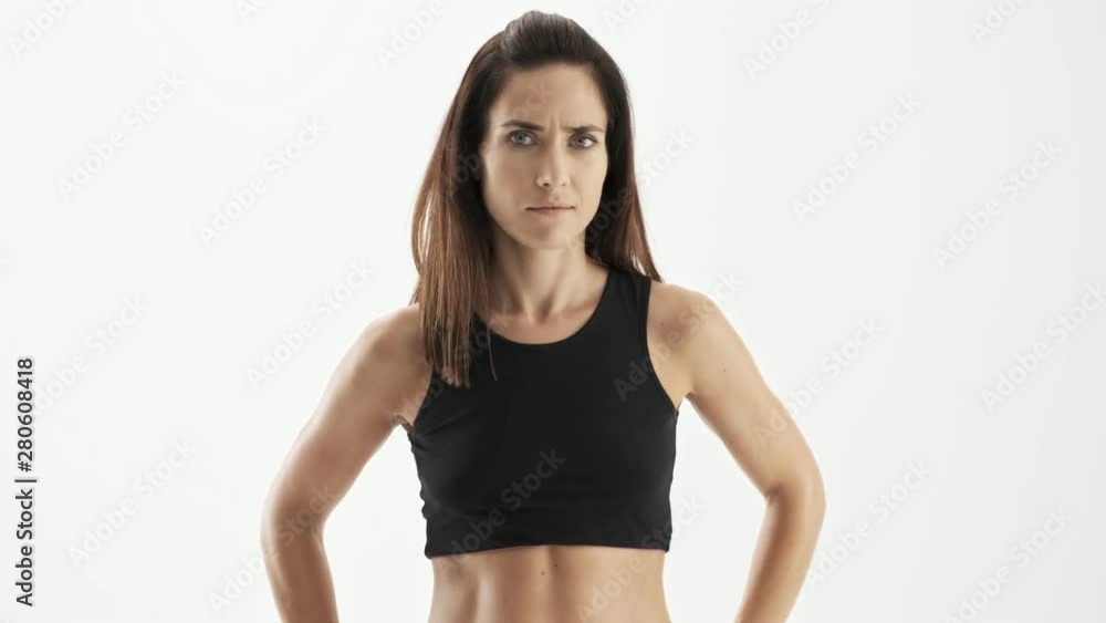 Upset beautiful sporty brunette woman in black sportswear shaking her head and gesturing with hand because of disagreeing with someone over white background isolated Upset beautiful sporty brunette woman in black sportswear shaking her head and gesturing with hand because of disagreeing with someone over white background isolated
