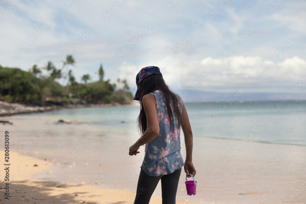 A young girl is searching for seashells in Maui, HI.