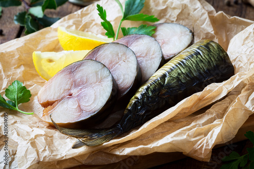 Fotografi Cold smoked mackerel fish on a parchment paper with parsley leaves and lemon wed