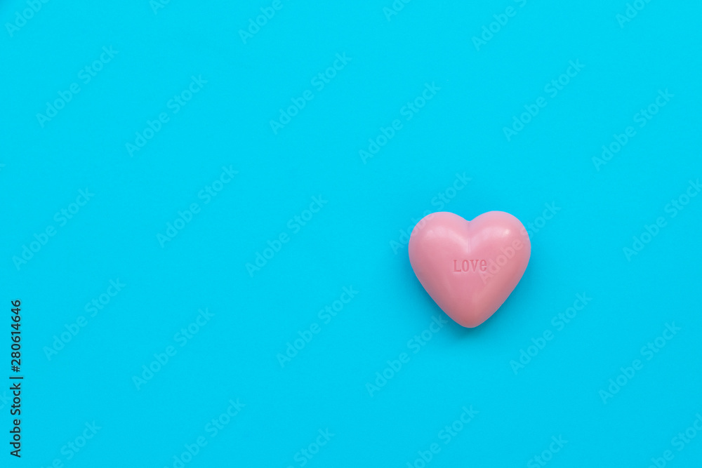 Pink soap in heart shape on blue background. Spa cosmetic or hygiene concept. Copy space. Flat lay. Top view.