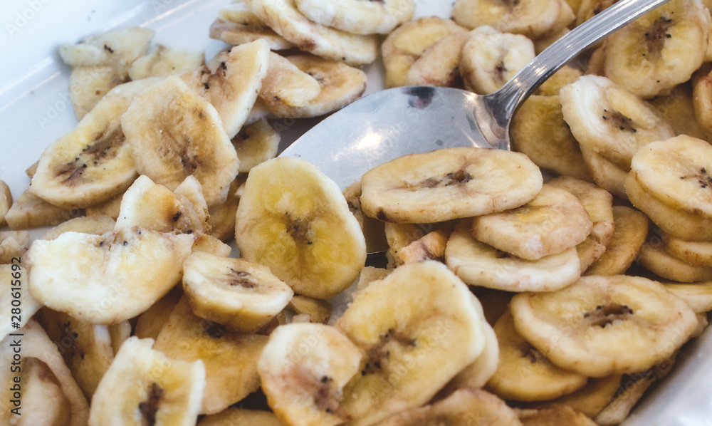 Banana chips in a white breakfast bowl with a spoon Banana chips in a white breakfast bowl with a spoon
