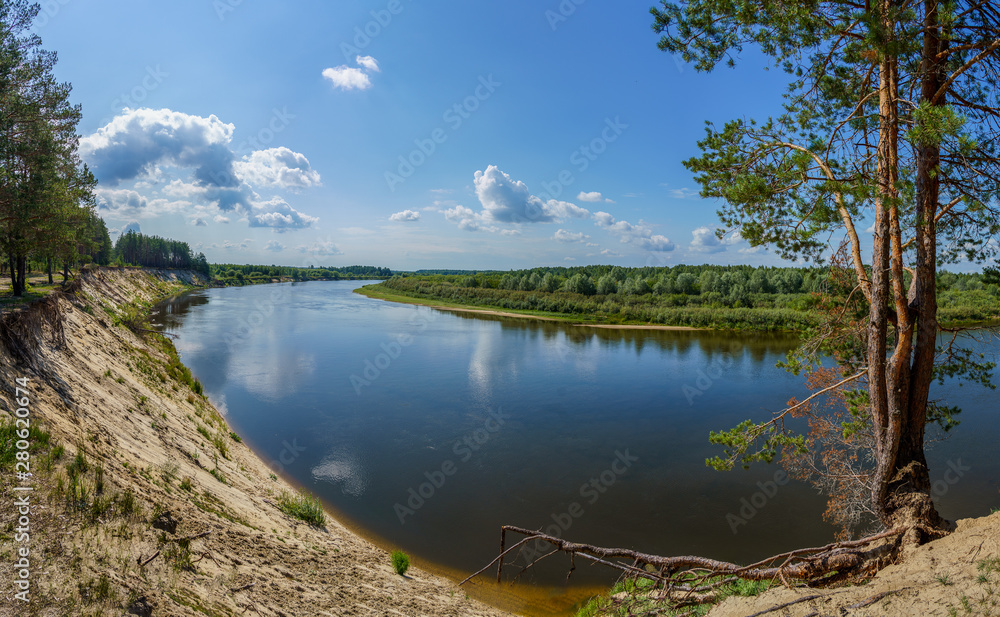 High steep river bank covered with forest and a view of the river and the horizon