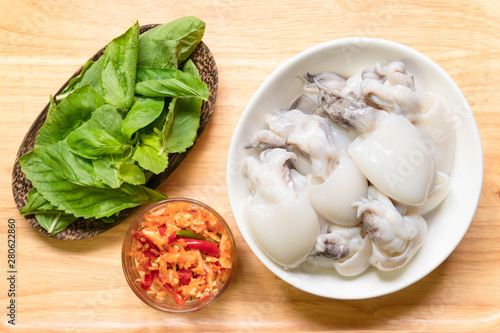 Cuttlefish or Cuttlefish Rainbow with holy basil leaves and pestle chili and garlic prepare for stir fried Cuttlefish with basil; top view on wooden background. Thailand's popular dishes (Pad Ga Pow).