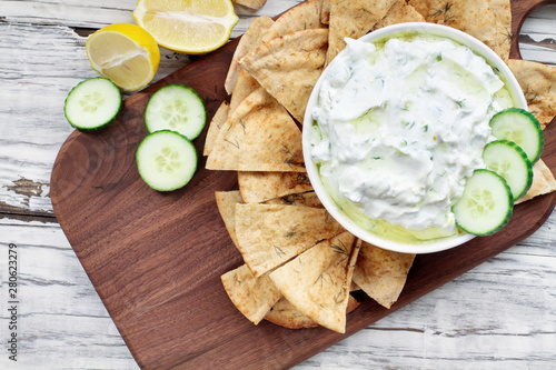 Traditional Greek Tzatziki dip sauce made with cucumber sour cream, Greek yogurt, lemon juice, olive oil and a fresh sprig of dill weed. Served with toasted Za'atar Pita bread.  Top view  or flat lay. photo