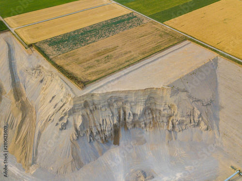 Aerial view of open cast gravel mine in Switzerland. Land grabbing for mining industry. Fields beside gravel quarry. photo