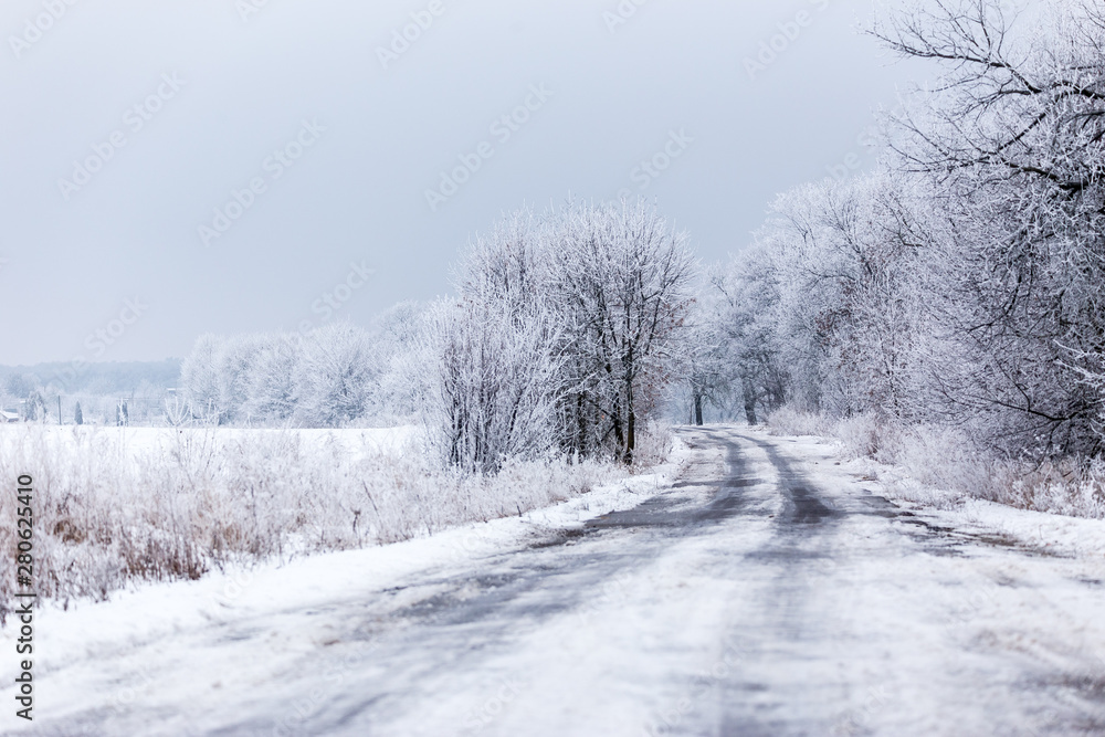 Winter rural road landscape with frozen asphalt path.