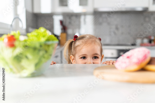 Young child choosing between salad or doughnut. Healthy clean detox eating concept.