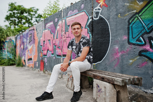 Lifestyle portrait of handsome man posing on the street of city with graffiti wall. © AS Photo Family
