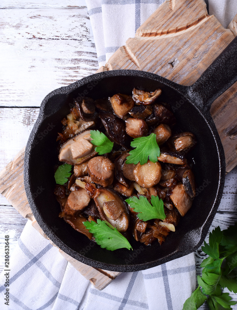 Roasted forest mushrooms topped with fresh parsley in a cast iron pan Roasted forest mushrooms topped with fresh parsley in a cast iron pan