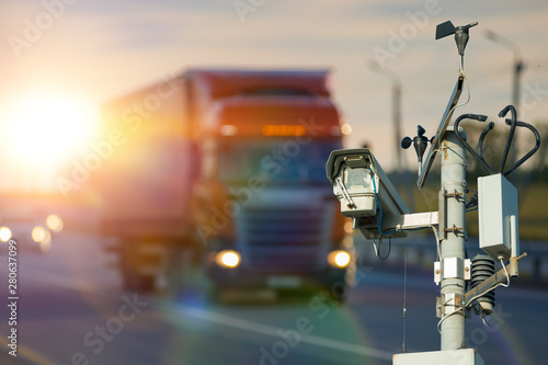 Truck with trailer and surveillance camera for traffic violations. Traffic intersection with signal lights. The concept of a police fine for speeding on the highway photo