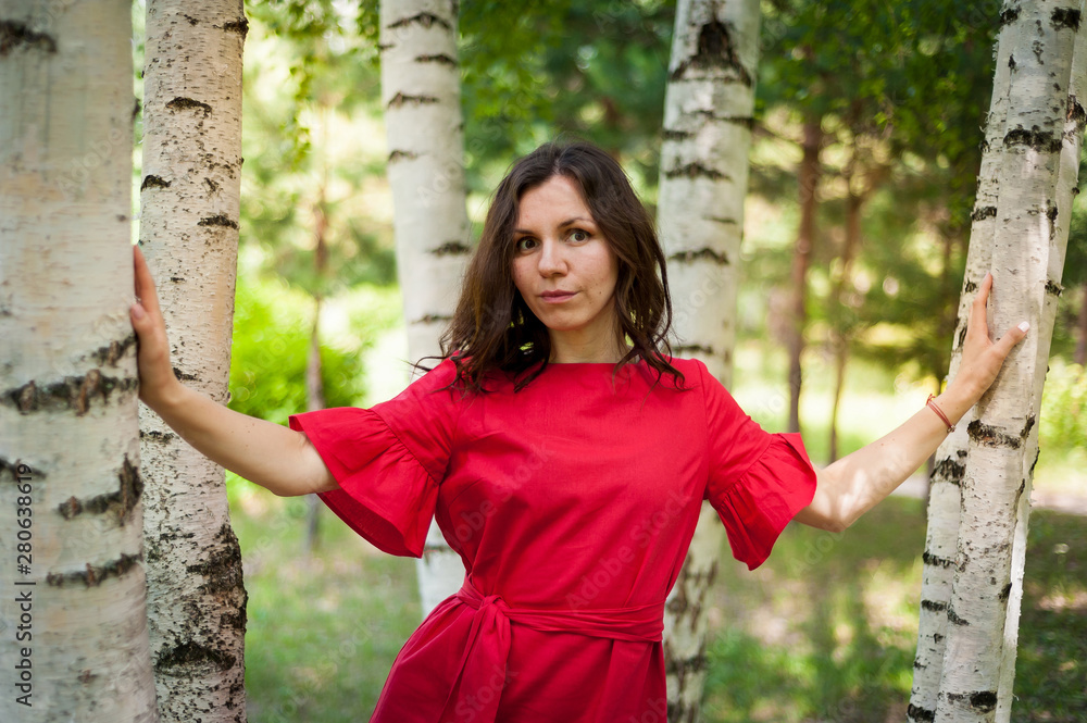 Beautiful brunette in a red dress walking in a Sunny Park Beautiful brunette in a red dress walking in a Sunny Park