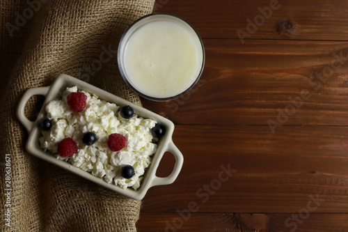 Composition with cottage cheese, fresh berries and yogurt on wooden table
