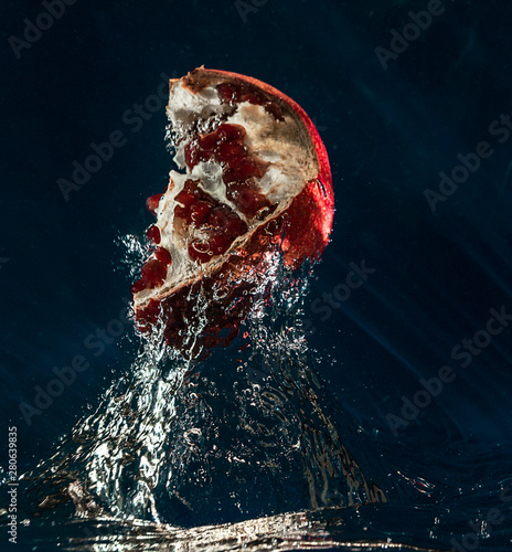 Juicy taste of the pomegranate. Freshness of summer. Fruits. Fruit freshness. Berries. Still-life. Pomegranate is like an explosion of taste. Red pomegranate on a blue background. The berries in the w