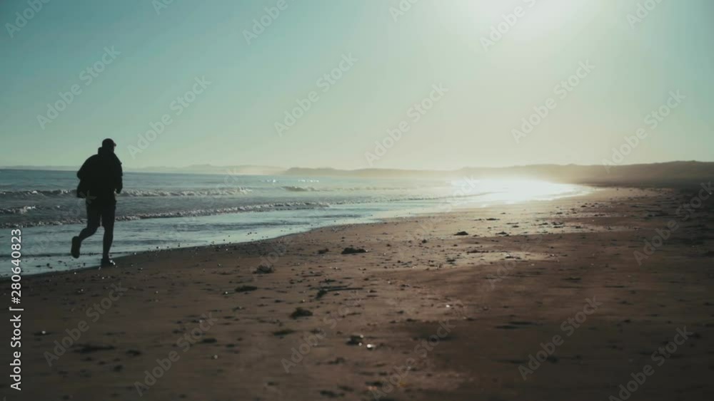 Man running on sandy beach during sunrise Man running on sandy beach during sunrise