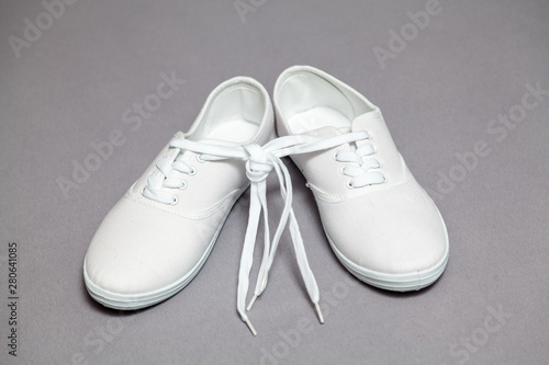 Pair of white sneakers standing on gray background