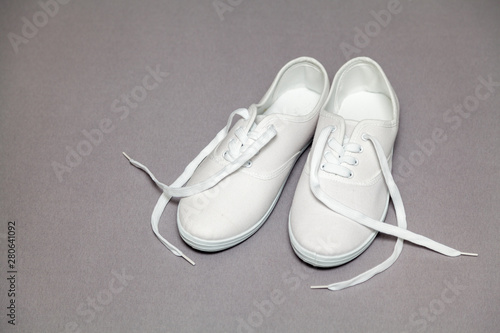 Pair of white sneakers standing on gray background