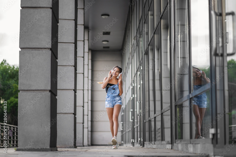 Photo of attractive young teenage girl walking with cellphone and earphones