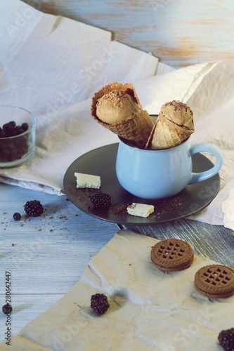  Chocolate ice cream in wafer cones, cookies, berries on a wooden table, dessert in the hot season, homemade treats